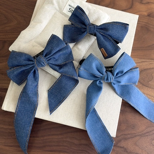 Macro detail of denim bow hair clips with contrast stitching and handmade labels