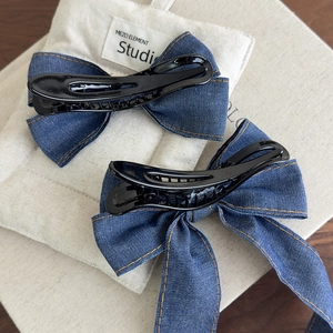 Detail of blue denim bow hair clips with retro yellow stitching and durable black grippers