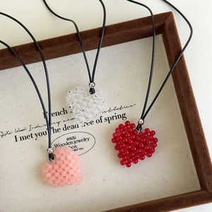 Détails de pendentifs cœurs en perles faits main en rose et rouge sur un plateau