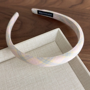 Detail of checkered fabric headband featuring a handmade label on a textured tray