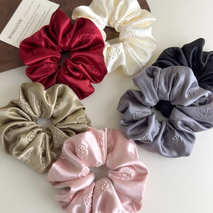 Dettaglio di elastici scrunchie in raso con rose a rilievo 3D in sei diversi colori