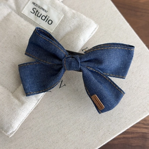 Detail of denim bow hair clip with orange stitching and Hand Made tag decoration