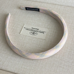 Detailed shot of pink and yellow plaid fabric headband with handmade textile label