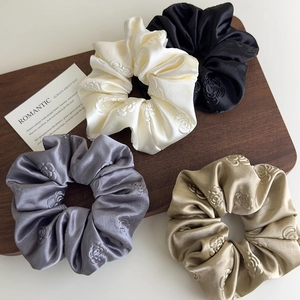 Dettaglio di quattro elastici in raso con jacquard rosa 3D in bianco, nero, grigio e oro