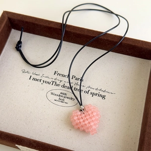 Gros plan d'un collier pendentif cœur en perles roses fait main sur un plateau à bijoux