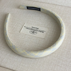 Detail of yellow and blue plaid headband featuring a handmade black fabric label