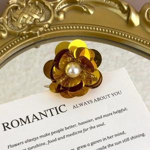Detailed macro view of handmade gold sequin flower shoe charm with a large pearl center