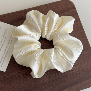 Vista dettagliata dello scrunchie in raso bianco crema con motivo a rose 3D a rilievo