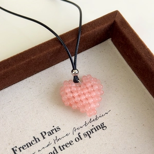 Détail macro du pendentif cœur en perles roses avec cordon noir et perle argentée de luxe