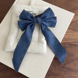Detailed macro of dark blue denim bow hair clip with orange contrast stitching details