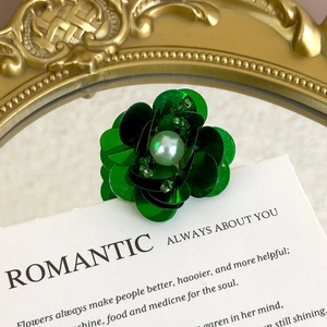 Detail of green sequin flower charm with iridescent pearl and bead center decoration