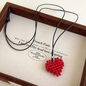 Détail d'un pendentif cœur en perles rouges fait main dans une boîte à bijoux de luxe