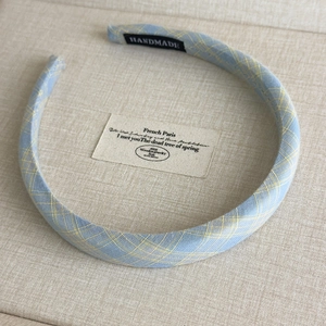 Detail of handmade light blue and yellow plaid fabric headband with artisan label