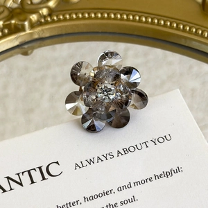 Macro detail of crystal flower shoe charm with grey gems on a gold metallic base
