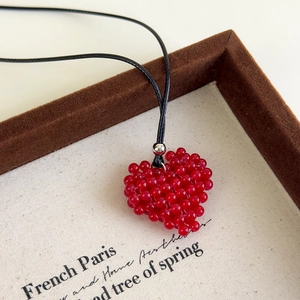 Détail macro d'un pendentif cœur en perles rouges fait main avec cordon ajustable