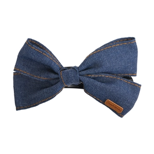 Detail of blue denim bow hair clip with orange stitching and brown Hand Made leather tag
