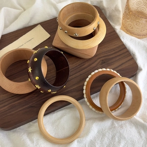 Collection of geometric wooden bangles with star studs and beads on a rustic tray