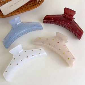 Detalle de pinzas para el cabello de acrílico con pedrería en varios tonos suaves y dulces