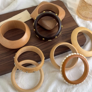 Collection of geometric wooden bangles with gold star studs and beads on a wooden tray