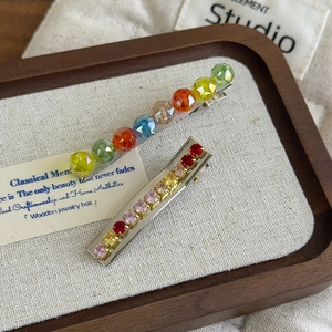 Colorful dopamine crystal hair clips set with gradient rhinestones on a wooden tray
