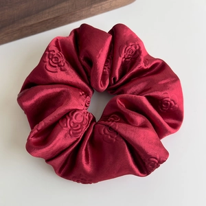 Macro dettagliata dell'elastico scrunchie rosso in satin con rose a rilievo 3D