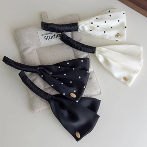 Detail view of four elegant satin polka dot banana hair clips with golden charms