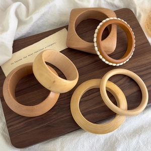 Close-up of geometric wooden bangles with star rivets and bead inlay on dark wood surface
