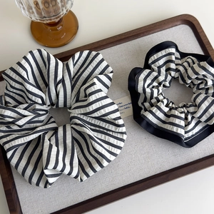 Detail of black and white striped fabric scrunchies on a wooden tray in minimalist style