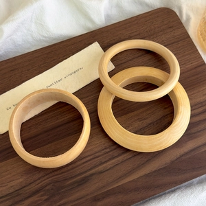 Detail view of three natural wood bangles with fine grain texture on linen background