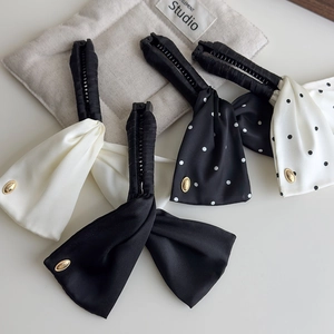 Detailed close-up of four satin polka dot banana hair clips with elegant gold metal buckles