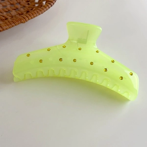 Primer plano de pinza para el cabello verde neón translúcida con brillantes dorados