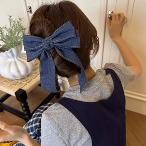 Stylish deep blue denim bow hair clip with orange stitching for a chic half-up hairstyle
