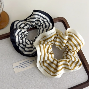 Detail of striped fabric scrunchies with satin edges on a rustic wooden tray