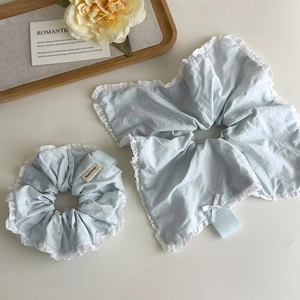 Close-up of light blue fabric scrunchie with lace trim and hand made label detail