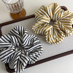 Oversized striped fabric scrunchies in yellow and black on a rustic wooden tray