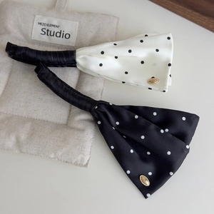 Detail of satin polka dot bow hair clips featuring gold accents and premium texture