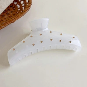 Detalle de una pinza para el cabello blanco crema con diamantes marrones en cesta tejida