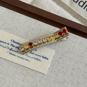 Close-up of vintage alligator hair clip with colorful crystal gems on silver base