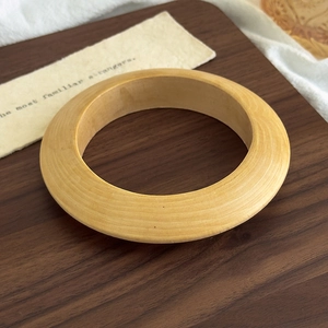 Detail of a natural wood bracelet featuring grain patterns on a rustic wooden tray