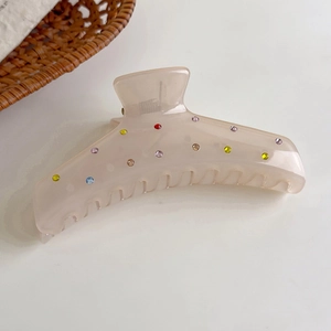 Primer plano de pinza para el cabello beige mate con pedrería de colores y lunares