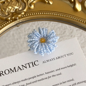 Detailed macro of handmade light blue beaded daisy flower shoe charm on card