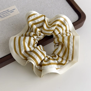 Detailed close-up of yellow and white striped fabric scrunchie on a wooden tray