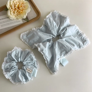 Close-up of light blue lace scrunchie with white embroidery and Hand Made label