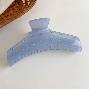 Detalle de pinza para el pelo azul gelatina con pedrería y mecanismo de resorte metálico