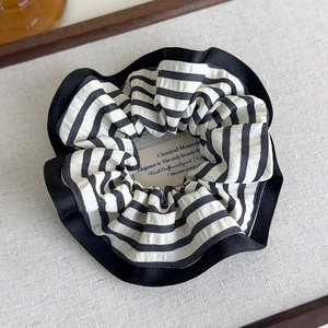 Detailed shot of black and white striped scrunchie with pleated black lace edges
