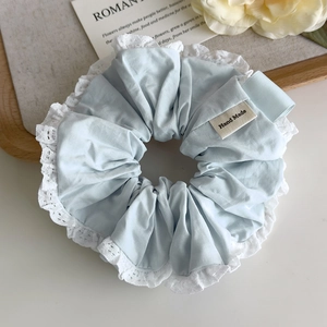 Detail of light blue scrunchie with white lace trim and Hand Made label on wood tray