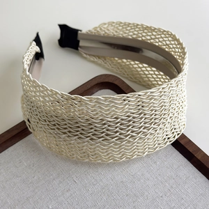 Close-up detail of cream woven headband showing hollow mesh texture and linen display tray
