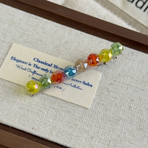Detail of multi-color faceted crystal bead hair clip on a vintage background card