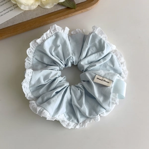 Detail of light blue scrunchie with lace trim and handmade label on a wooden tray