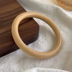 Detailed view of smooth natural wood grain texture on a geometric round wooden bangle